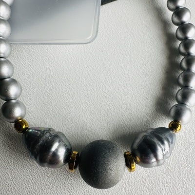 Colar com contas prateadas e douradas sobre fundo branco e preto