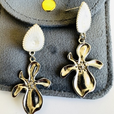 Brincos dourados com base branca em saco cinza