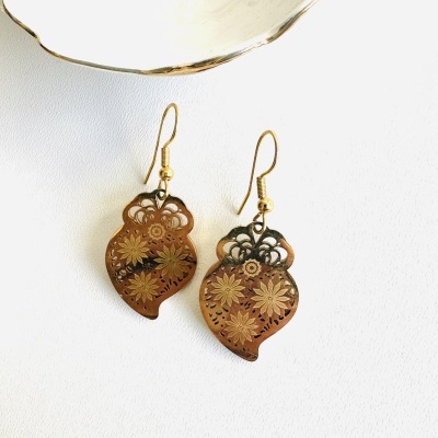 Brincos dourados com padrão floral e bacia de cerâmica branca com borda dourada