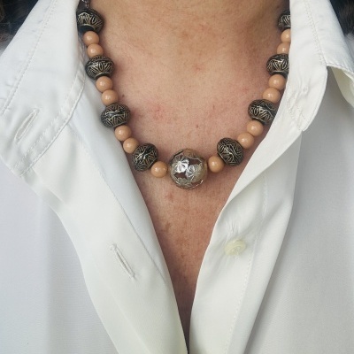 Colar com contas escuras e bege com padrão de folhas