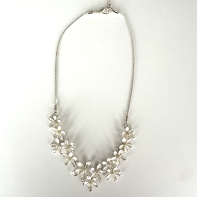 Colar prateado com flores estilizadas sobre fundo branco