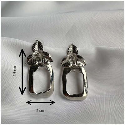 Brincos prateados com desenho de folhas sobre tecido branco