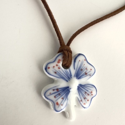 Colar com pendente em forma de trevo branco com padrões azuis e vermelhos