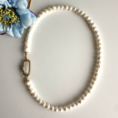 Colar de pérolas com fecho dourado e flor azul ao lado