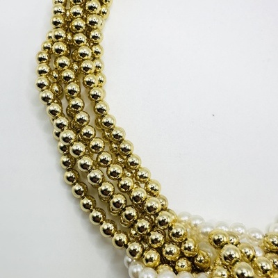 Colar de contas douradas e brancas em fundo branco