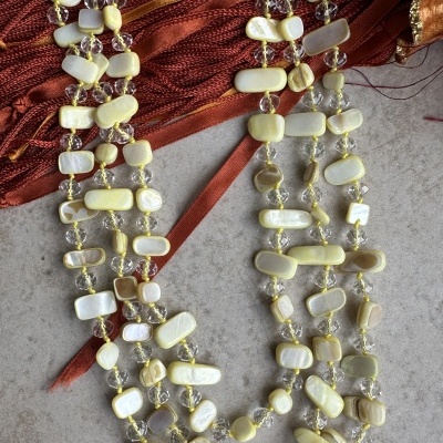 Colar de pedras creme e brancas com fecho metálico sobre tecido vermelho