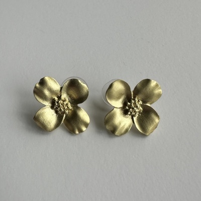 Brincos dourados em forma de flor com quatro pétalas em fundo branco.