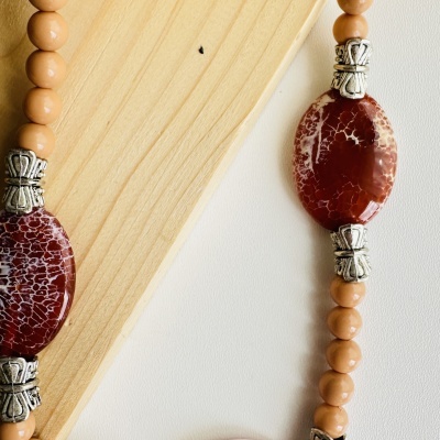 Colar com contas ovais vermelhas com padrão branco e contas esféricas bege com detalhes metálicos prateados