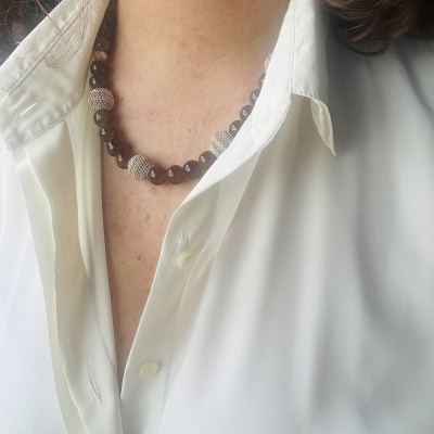 Colar com contas castanhas e prateadas usado com camisa branca