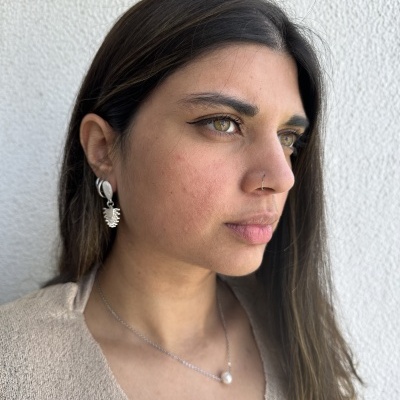 Mulher com colar de pérola e brincos prateados contra fundo branco