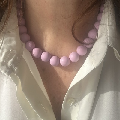 Colar de bolas lilás grandes em pescoço com camisa branca