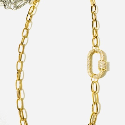 Colar tipo corrente dourada com fecho decorativo brilhante sobre fundo branco e correntes prateadas ao fundo