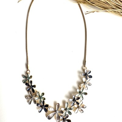 Colar com flores metálicas em tons variados sobre fundo branco com raminhos secos