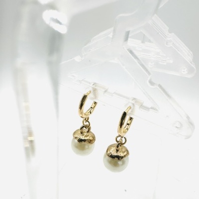 Brincos dourados com pérola pendente num suporte transparente