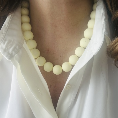 Colar de contas creme sobre camisa branca