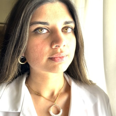 Mulher jovem com joias e camisa branca em fundo claro