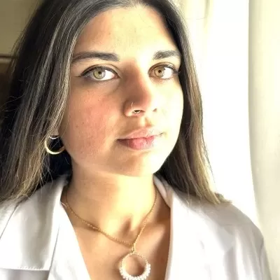 Colar dourado com pendente circular branco e mulher com blusa branca