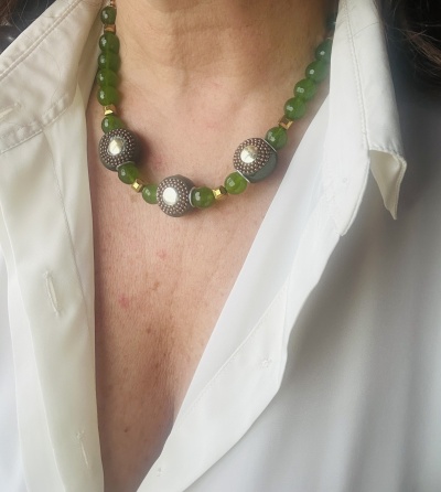 Colar com contas verdes e contas grandes decoradas usado com camisa branca