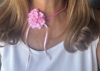 Colar rosa com flor de tecido e cordão fino em pescoço