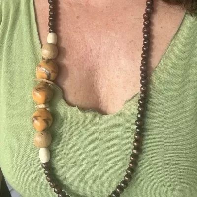 Colar de contas de madeira em diferentes tamanhos e cores sobre camisola verde