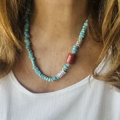Colar de contas azul turquesa com conta vermelha e prata ao pescoço