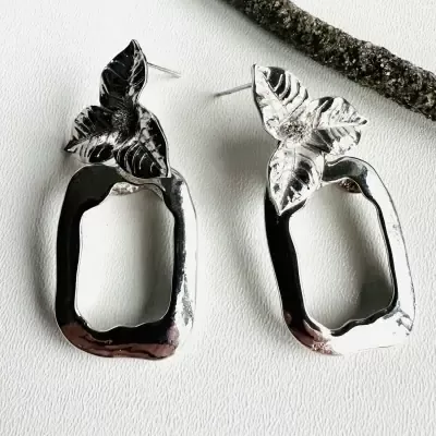 Brincos prateados com folhas e formas geométricas