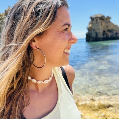 Mulher a usar colar de conchas naturais e argola grande junto ao mar