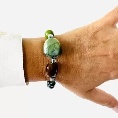 Pulseira com pedras verdes e castanhas em pulso