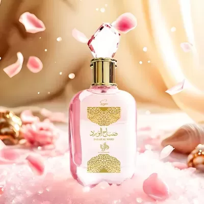 Frasco de perfume rosa com tampa de gema e detalhes dourados em ambiente com pétalas de rosa