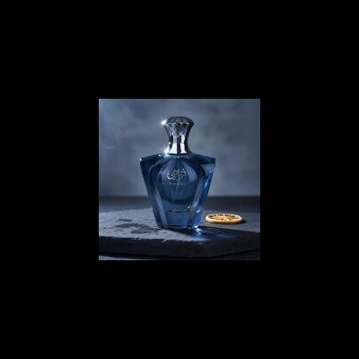 Frasco azul translúcido de perfume com tampa prateada e rodela de laranja seca ao lado