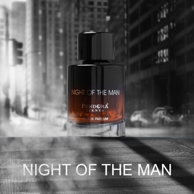 Frasco de perfume Night of the Man com base laranja e tampa preta numa rua urbana cinzenta