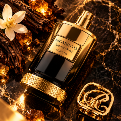 Frasco de perfume dourado e preto MOMENTO Liquid Gold sobre mármore com elementos naturais