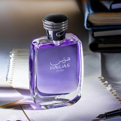 Frasco de perfume HAWAS For Him roxo com tampa prateada em papel com caneta e livros