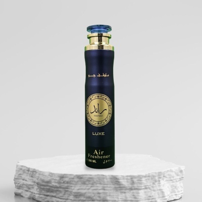 Frasco preto e dourado de ambientador com texto em árabe e inglês sobre superfície branca
