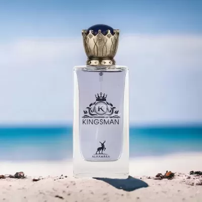 Frasco de perfume Kingsman com tampa dourada e azul na areia da praia