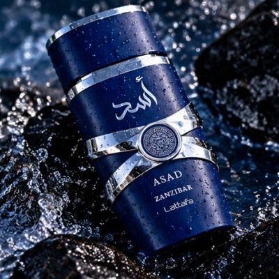Frasco de perfume azul escuro com texto ASAD ZANZIBAR Lattafa sobre pedras molhadas