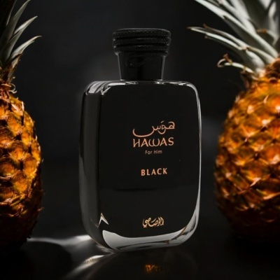 Frasco de perfume preto com texto dourado entre duas ananases