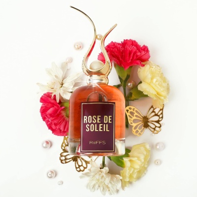Frasco de perfume Rose de Soleil com flores e decoração em fundo branco