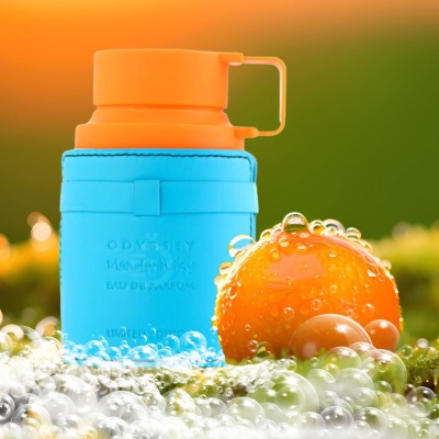 Frasco de perfume azul e laranja com texto, rodeado por bolhas e uma bola laranja molhada