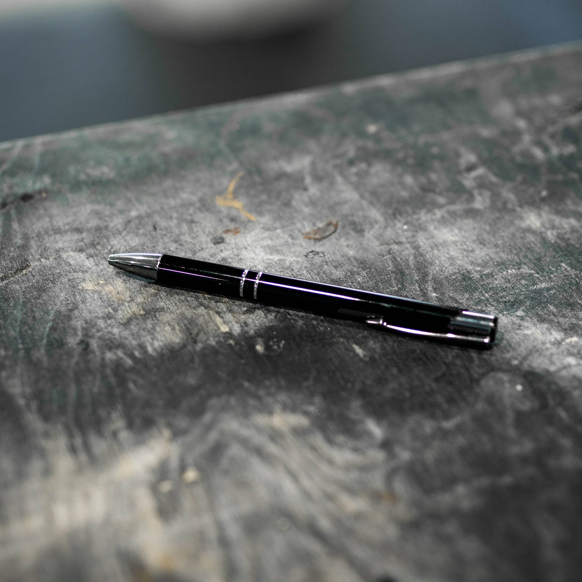 Air Release Pen - Bubble Pen Caneta esferográfica preta com detalhes prateados sobre superfície cinza texturizada