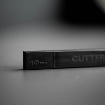 Caixa preta com texto '10 PCS' e 'CUTTER' numa superfície escura