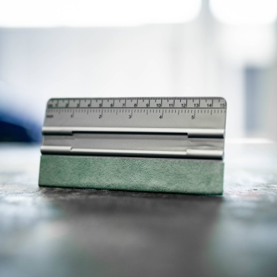 Régua metálica prateada sobre suporte verde com fundo desfocado