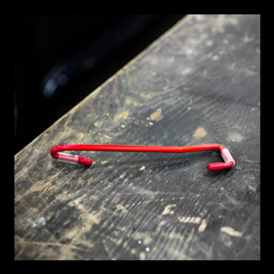 Gancho metálico vermelho sobre madeira escura desgastada