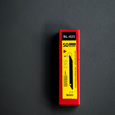 Embalagem vermelha e amarela de lâminas de corte SK2 9mm com texto e instruções