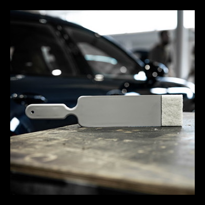 Pá cinzenta com cabo em superfície de madeira ao lado de um carro azul