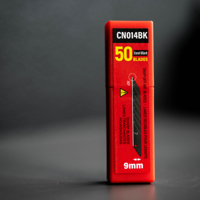 Embalagem vermelha para lâminas de barbear 9mm sobre fundo escuro