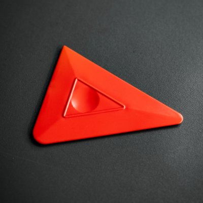 Triângulo de plástico vermelho fosco sobre superfície preta