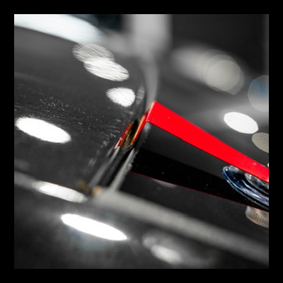 Ponteiro vermelho de relógio sobre mostrador preto com linhas vermelhas e reflexos de luz