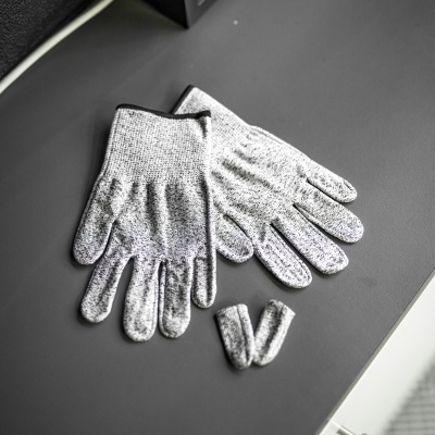 Luvas cinzentas de malha sobre superfície preta com moldura ao fundo