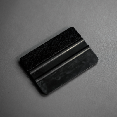Raspador preto de plástico com superfície texturizada numa mesa cinzenta